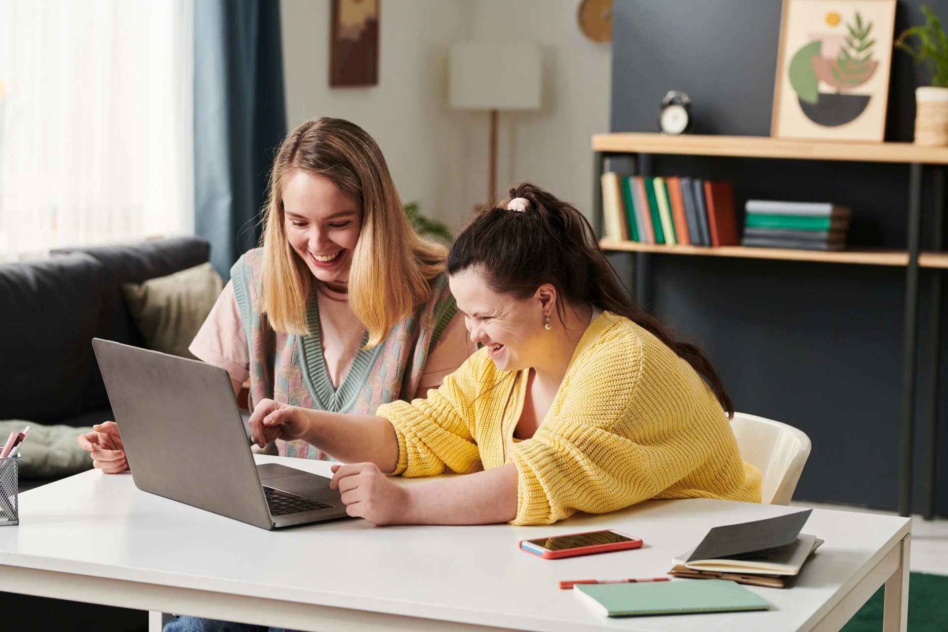 A woman and girl smiling at a laptop